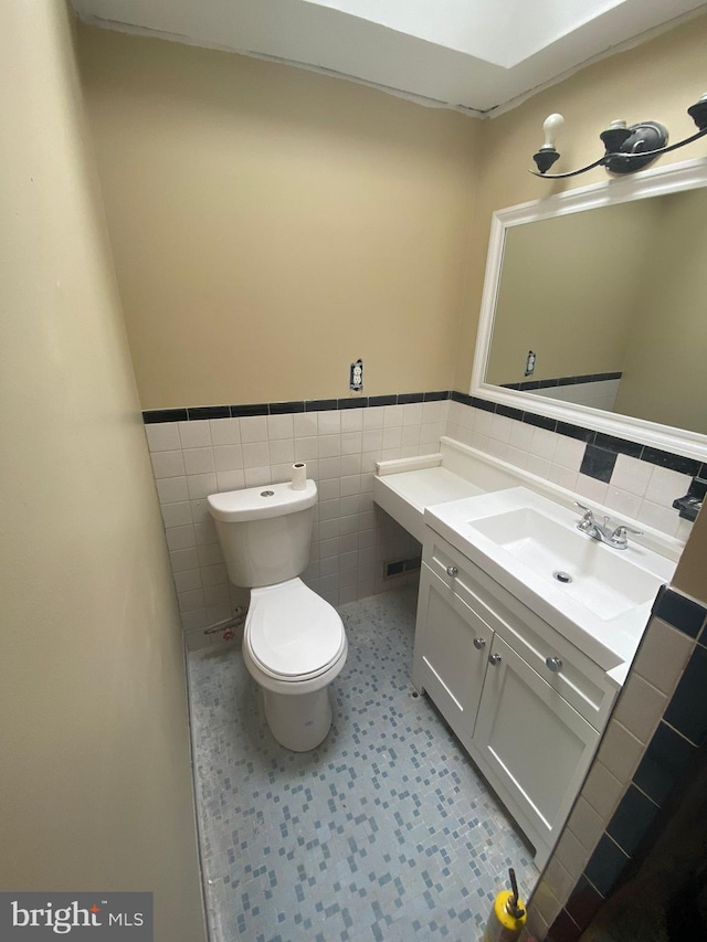 bathroom featuring vanity, tile walls, and toilet