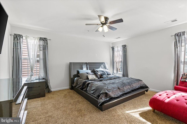 carpeted bedroom with visible vents, baseboards, and a ceiling fan