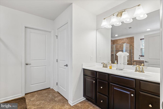 full bath with a shower stall, double vanity, baseboards, and a sink