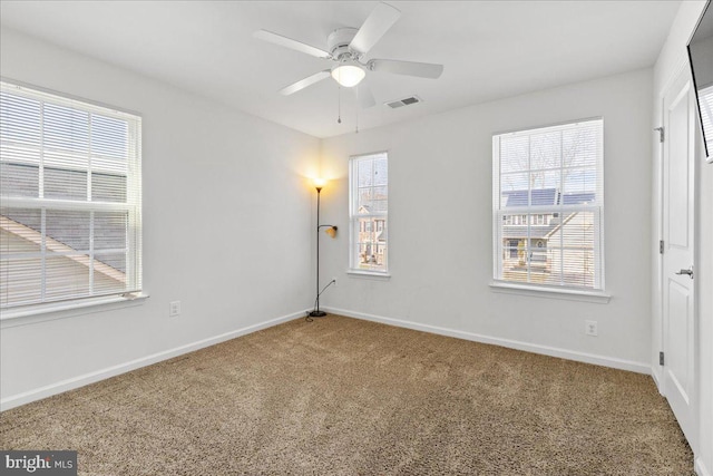 carpeted spare room featuring visible vents, baseboards, and ceiling fan