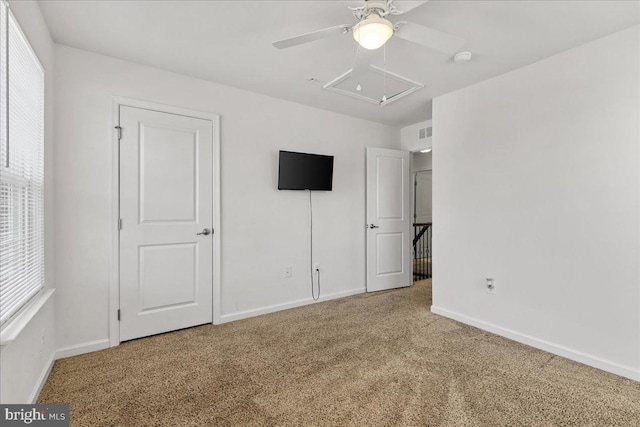 unfurnished bedroom with carpet flooring, ceiling fan, attic access, and baseboards