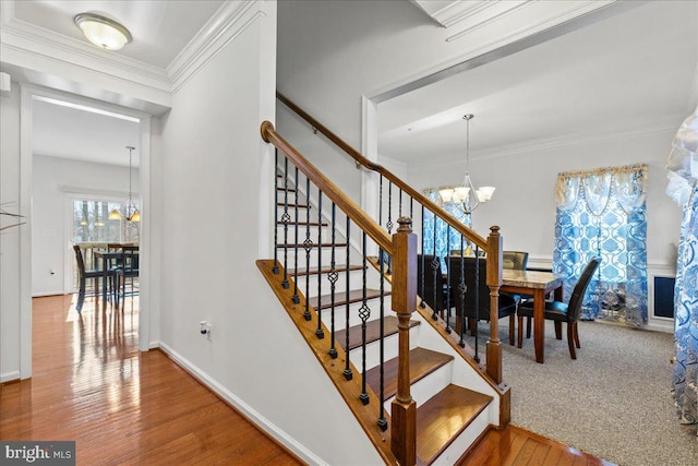 stairs featuring crown molding, wood finished floors, and a chandelier