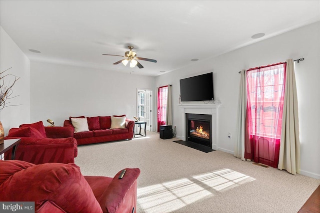 living room featuring a wealth of natural light, a fireplace with flush hearth, baseboards, and ceiling fan