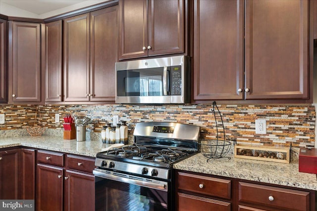 kitchen with light stone counters, tasteful backsplash, appliances with stainless steel finishes, and dark brown cabinetry