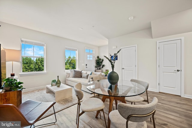 dining area with vaulted ceiling and light wood-type flooring