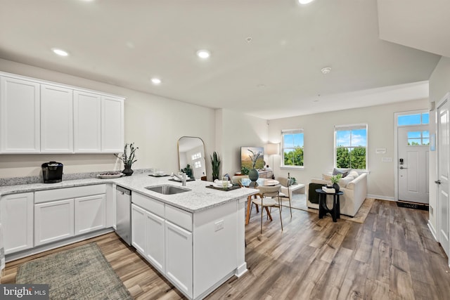 kitchen with dishwasher, sink, white cabinets, light stone counters, and kitchen peninsula