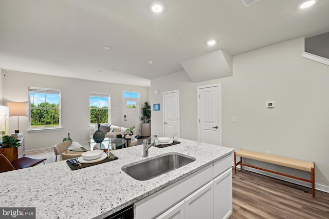 kitchen with lofted ceiling, sink, hardwood / wood-style flooring, white cabinetry, and light stone counters