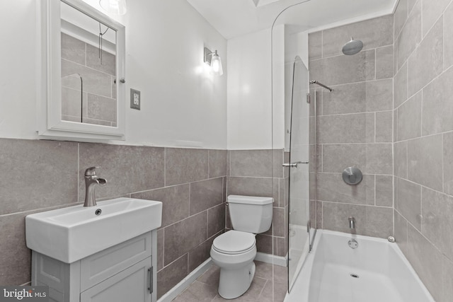 full bathroom with tiled shower / bath, tile walls, tile patterned flooring, vanity, and toilet