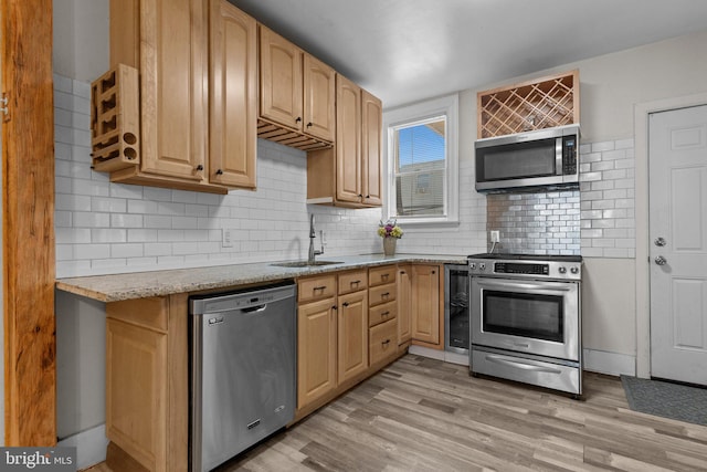 kitchen featuring appliances with stainless steel finishes, sink, decorative backsplash, light brown cabinets, and light wood-type flooring