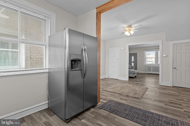 kitchen featuring stainless steel refrigerator with ice dispenser, wood-type flooring, radiator, and ceiling fan