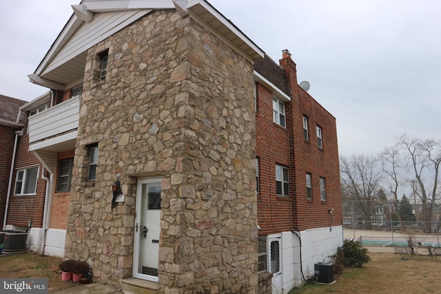 view of side of property with cooling unit and a balcony