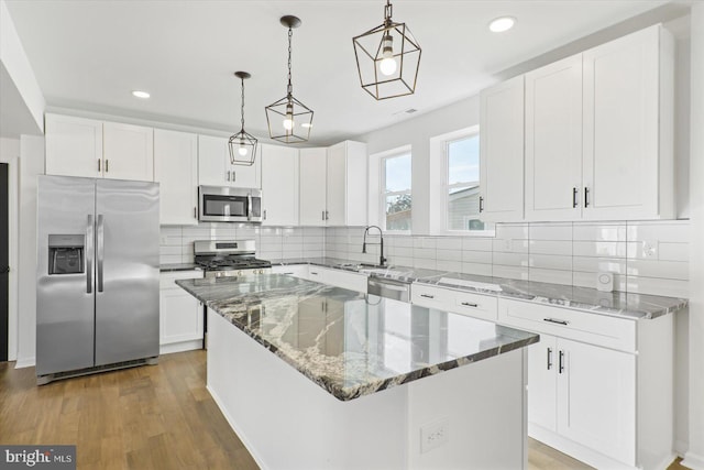 kitchen with stainless steel appliances, a center island, hanging light fixtures, and white cabinets