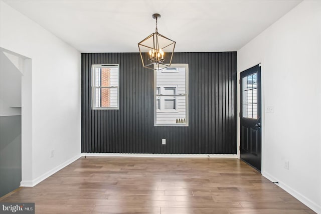 unfurnished dining area with an inviting chandelier, hardwood / wood-style floors, and a wealth of natural light