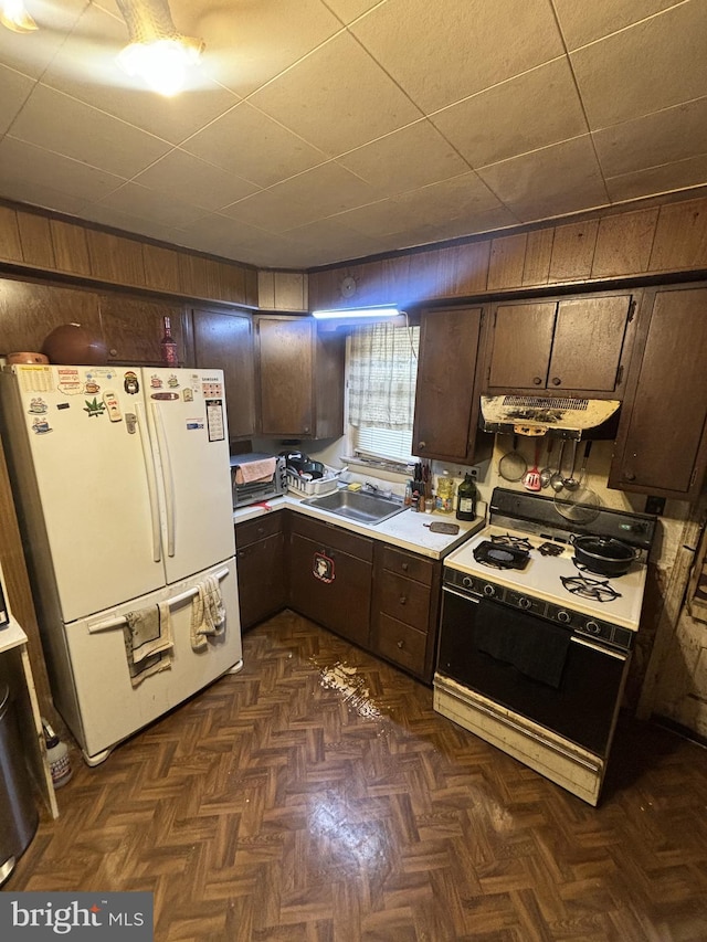 kitchen with white appliances, dark brown cabinetry, and sink