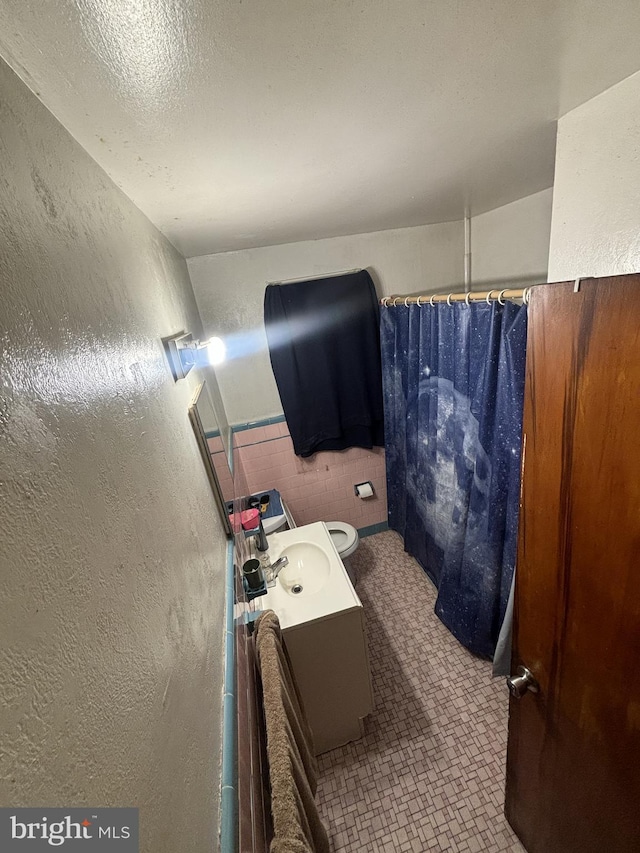 bathroom with a shower with shower curtain, vanity, a textured ceiling, tile patterned floors, and toilet