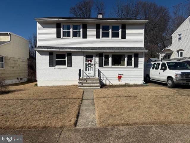 traditional-style house with entry steps and a front lawn