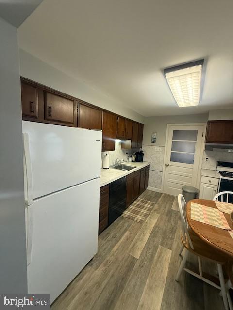 kitchen with light wood finished floors, light countertops, freestanding refrigerator, dark brown cabinetry, and range