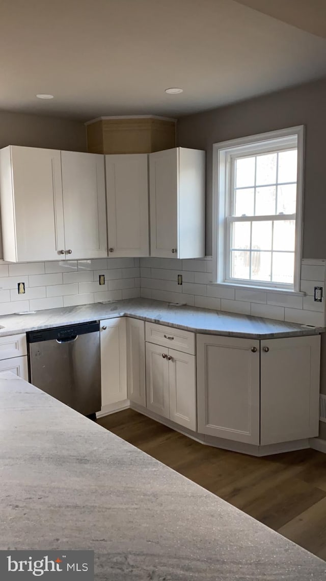 kitchen featuring dark hardwood / wood-style floors, stainless steel dishwasher, and white cabinets