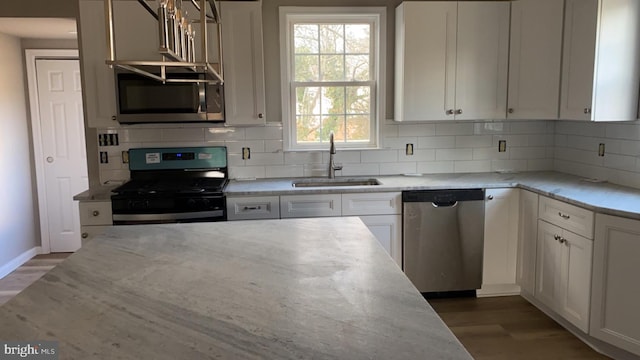 kitchen with sink, light stone counters, appliances with stainless steel finishes, dark hardwood / wood-style floors, and white cabinets