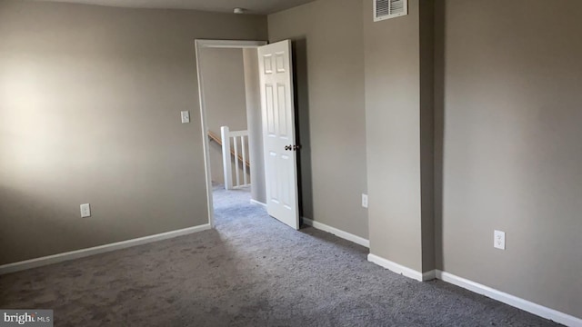 spare room with dark colored carpet