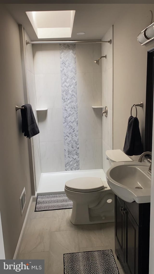 bathroom with vanity, tiled shower, and toilet