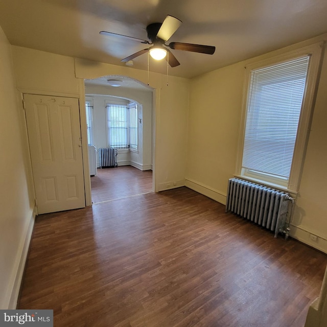 empty room featuring ceiling fan, dark hardwood / wood-style floors, and radiator