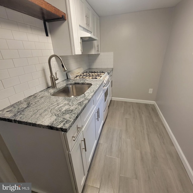 kitchen with sink, gas range gas stove, white cabinets, and stone counters