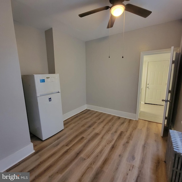 interior space featuring radiator, ceiling fan, and light wood-type flooring