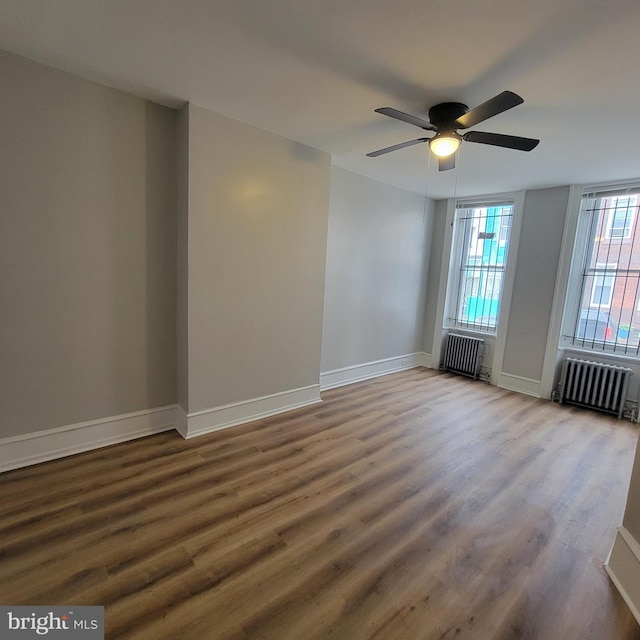 spare room featuring hardwood / wood-style flooring, ceiling fan, and radiator heating unit