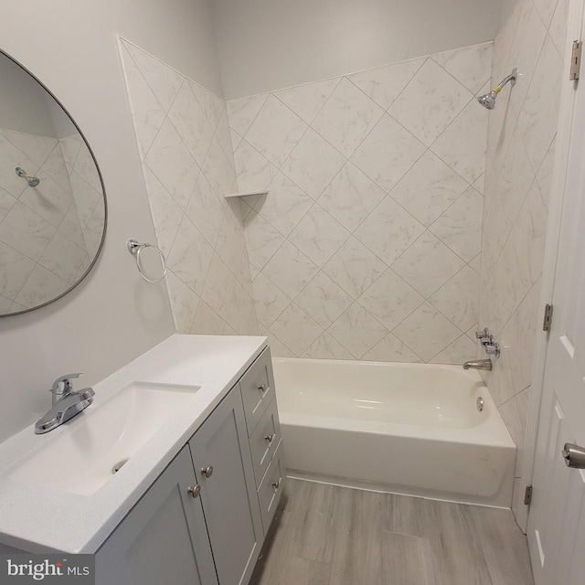 bathroom with hardwood / wood-style flooring, tiled shower / bath, and vanity