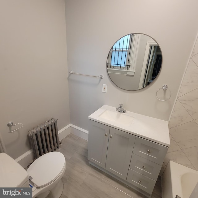 bathroom with vanity, toilet, radiator, and a washtub