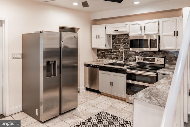 kitchen with appliances with stainless steel finishes, sink, white cabinets, decorative backsplash, and ceiling fan