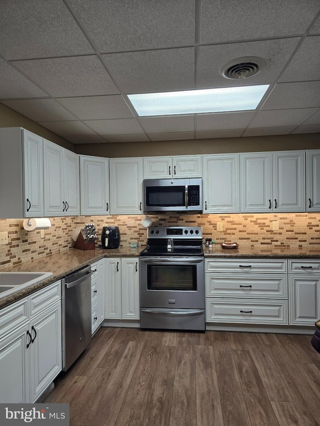 kitchen featuring white cabinetry, stainless steel appliances, dark hardwood / wood-style floors, and decorative backsplash