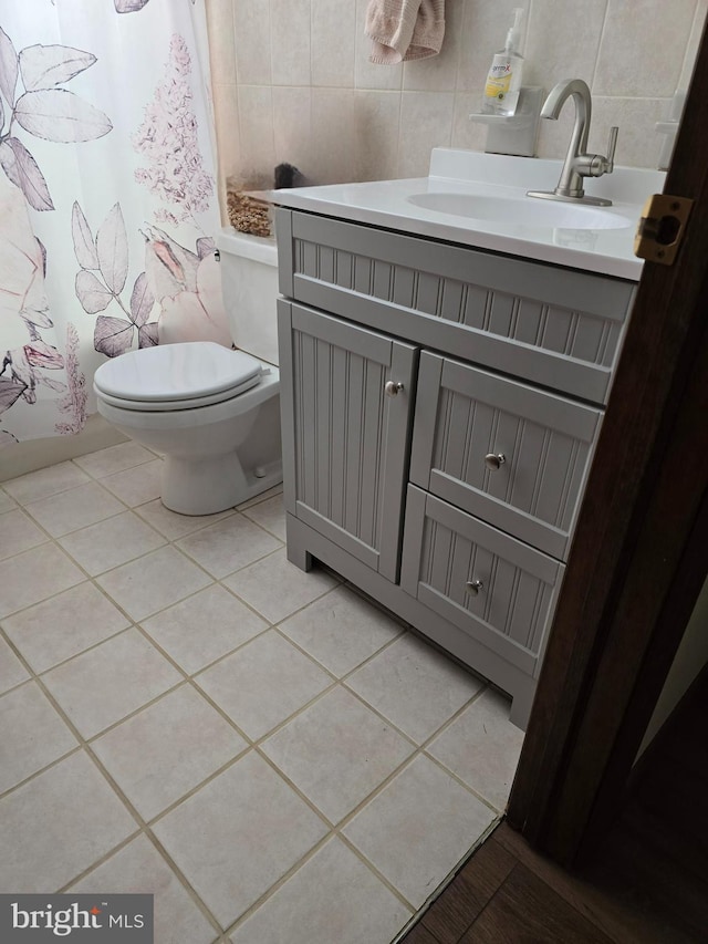 bathroom with tile patterned flooring, vanity, tile walls, and toilet