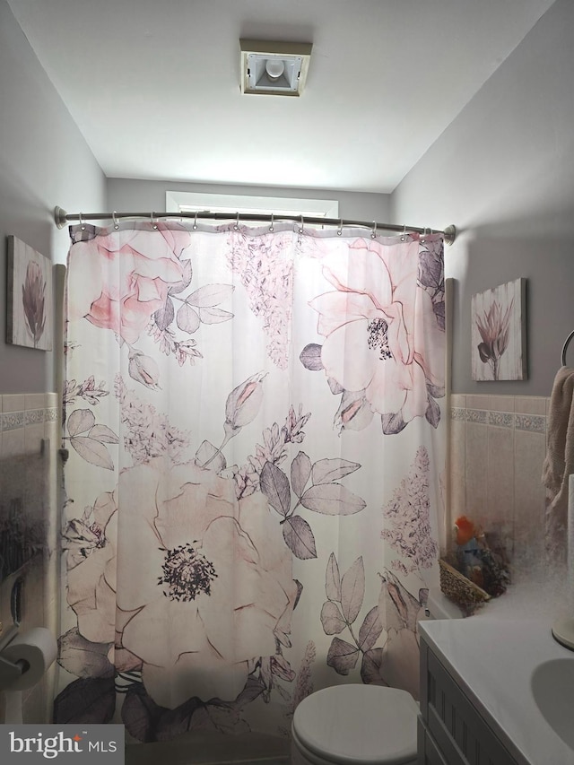 bathroom with vanity, curtained shower, tile walls, and toilet