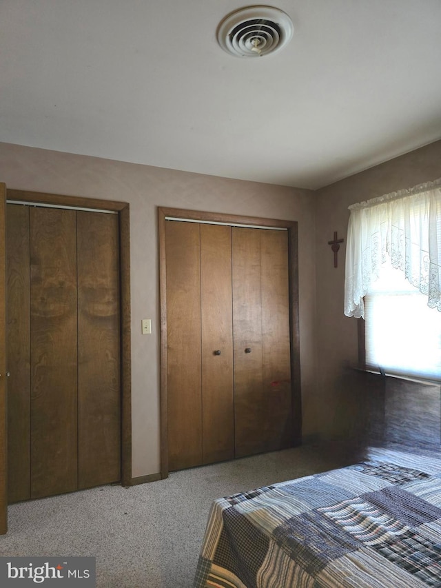 unfurnished bedroom featuring multiple closets and dark colored carpet