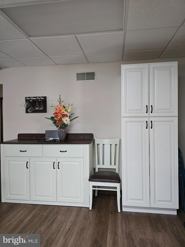 bar with white cabinetry, dark hardwood / wood-style floors, and a paneled ceiling