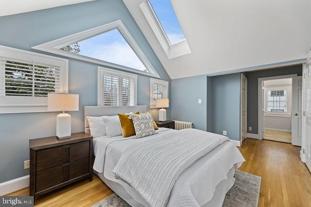 bedroom with multiple windows, radiator, light hardwood / wood-style floors, and a skylight