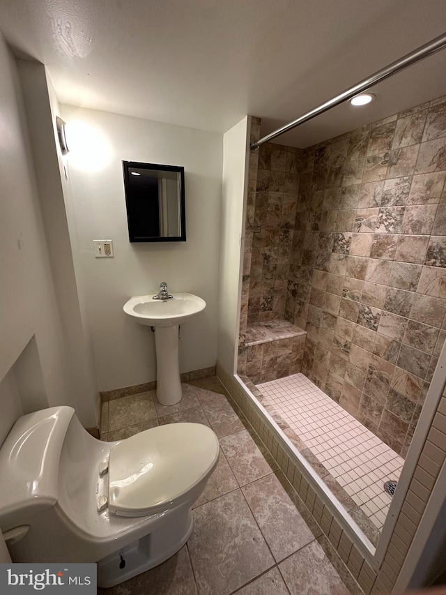 bathroom featuring tile patterned flooring, tiled shower, and toilet