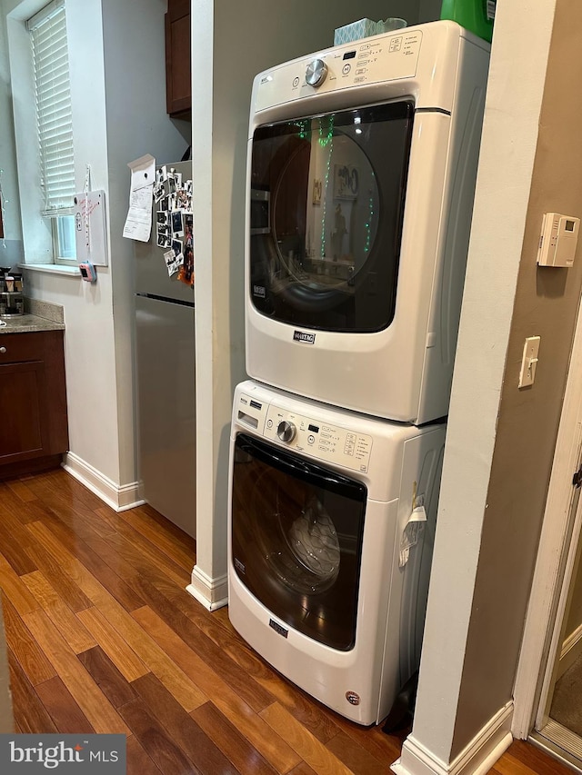 laundry room with stacked washer and clothes dryer and dark hardwood / wood-style flooring