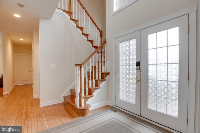 foyer featuring french doors, a towering ceiling, and light hardwood / wood-style floors