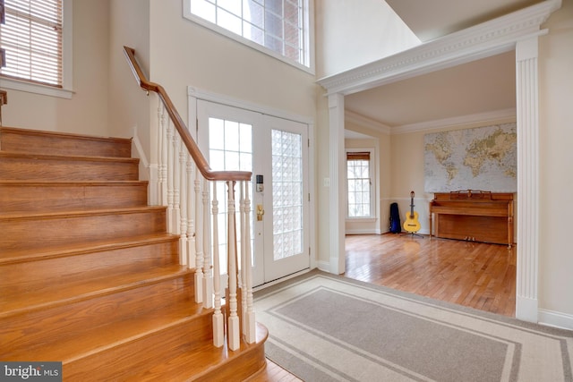 foyer entrance with a towering ceiling, french doors, hardwood / wood-style floors, and crown molding