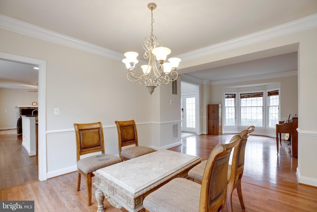 dining area featuring light hardwood / wood-style floors, a wealth of natural light, and crown molding