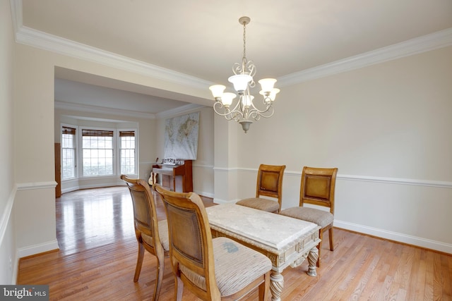 dining area featuring light wood-type flooring, a chandelier, and crown molding