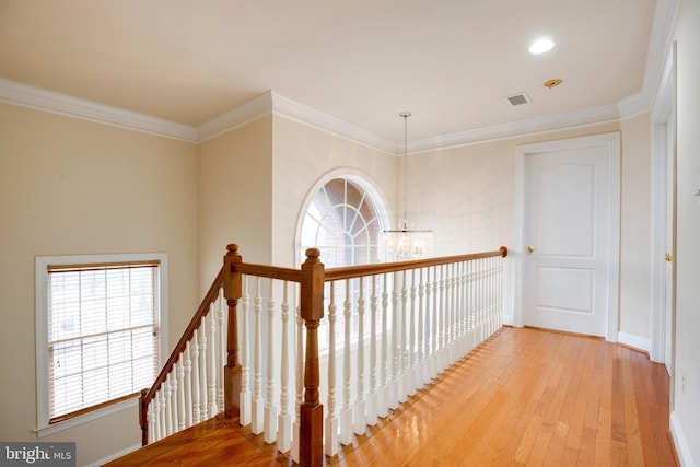 hallway featuring ornamental molding, light hardwood / wood-style flooring, and a notable chandelier