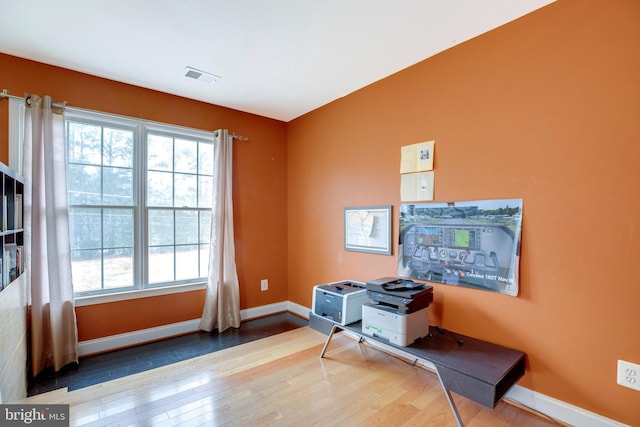 office with hardwood / wood-style flooring and a healthy amount of sunlight