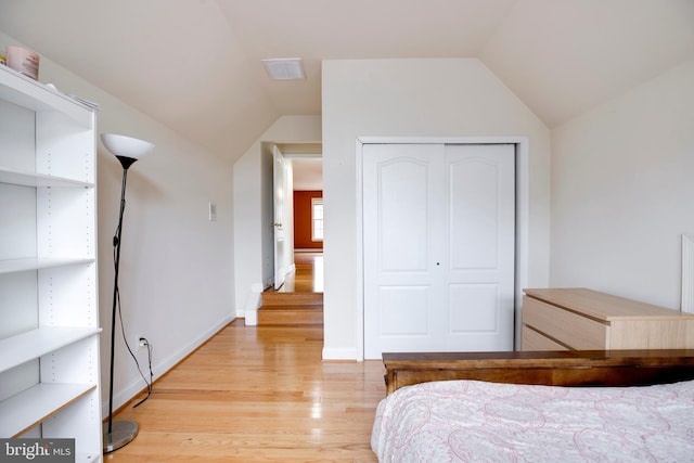 bedroom featuring light hardwood / wood-style flooring, vaulted ceiling, and a closet