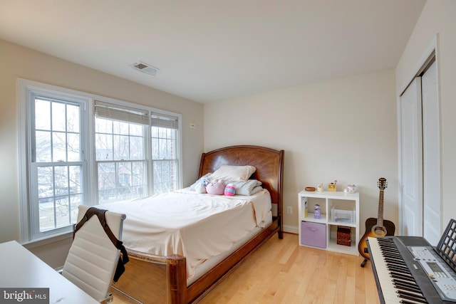 bedroom with multiple windows, a closet, and light wood-type flooring