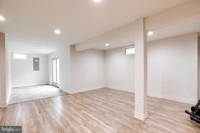 basement with electric panel and light hardwood / wood-style flooring