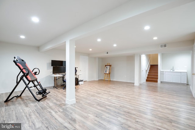 exercise area with light wood-type flooring and sink